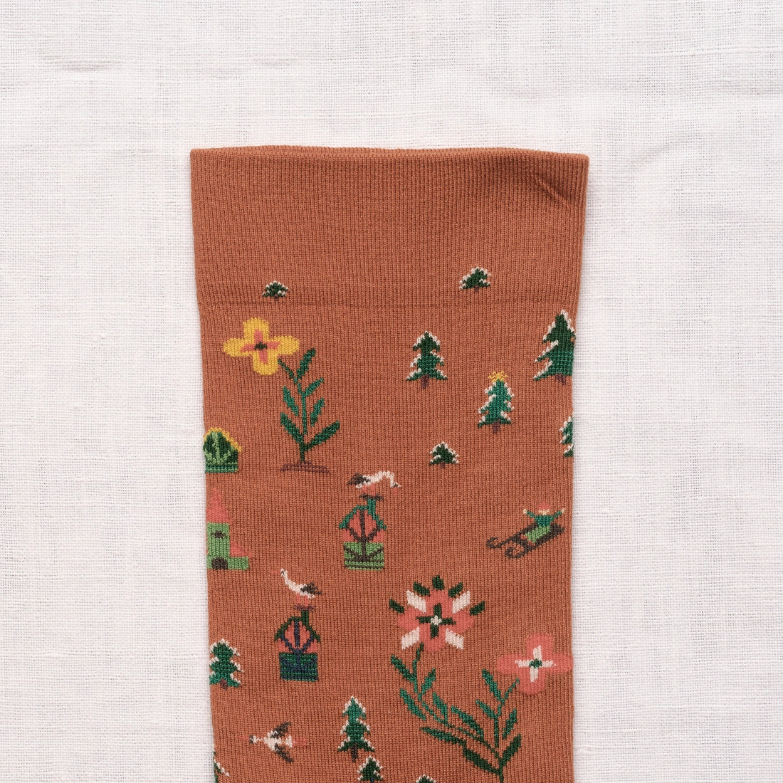 Bonne Maison Cinnamon Seed Socks, close-up of the cuff showing the scattered botanical motifs on a cinnamon ground

