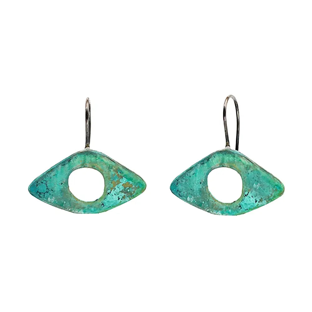 Pair of Sibilia Seeing Eyes Earrings in Turquoise Patina, featuring eye-shaped treated brass pendants with a circular cutout and mottled turquoise-green patina finish, hanging from silver wire hooks, on a white background