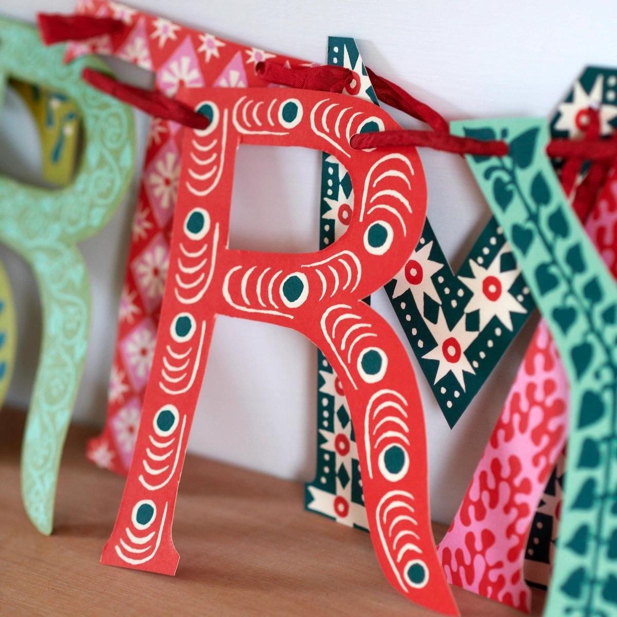 Colorful paper letters spelling 'R' on a wooden surface with a white background