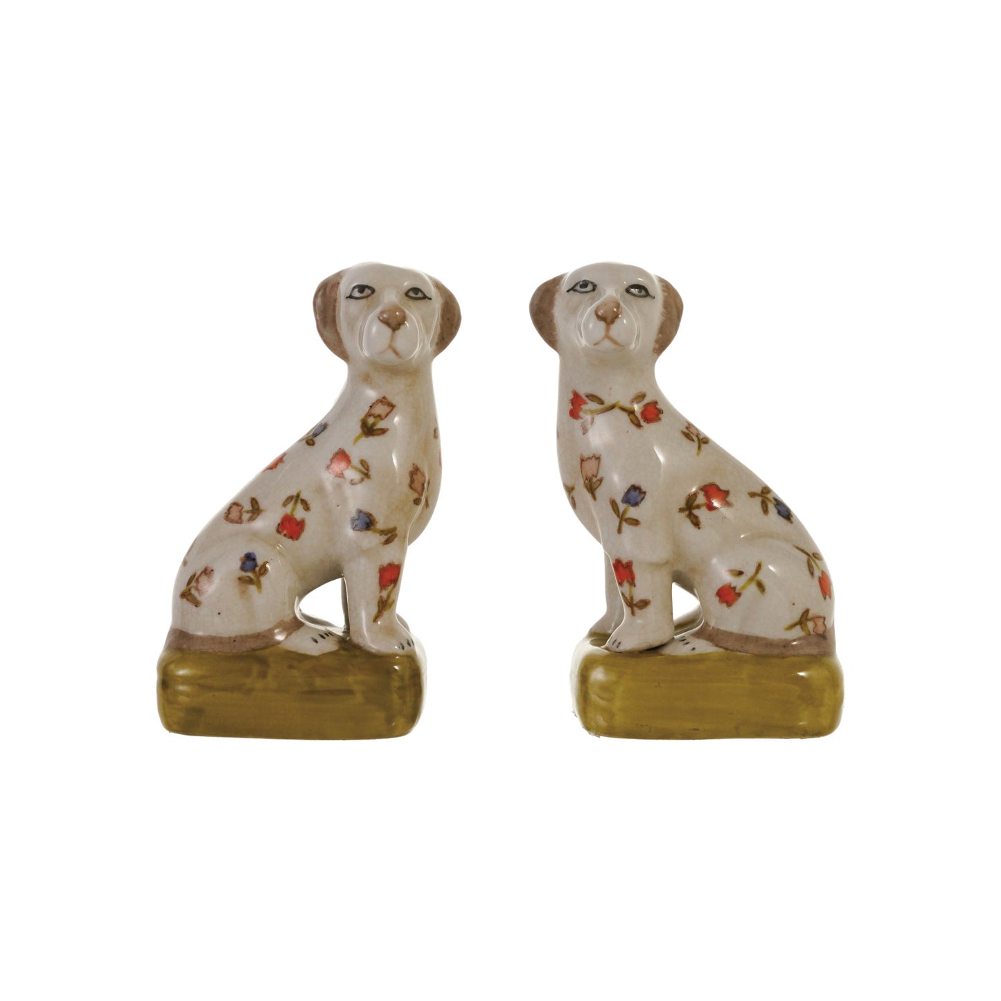 A pair of ceramic dog figurines sitting on rectangular bases, decorated with small floral motifs in red, blue, green, and brown on an off-white glazed background.