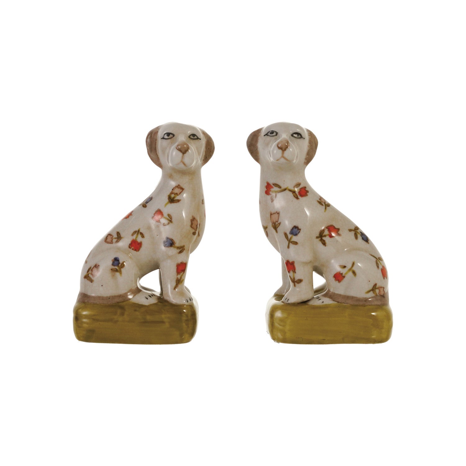 A pair of ceramic dog figurines sitting on rectangular bases, decorated with small floral motifs in red, blue, green, and brown on an off-white glazed background.