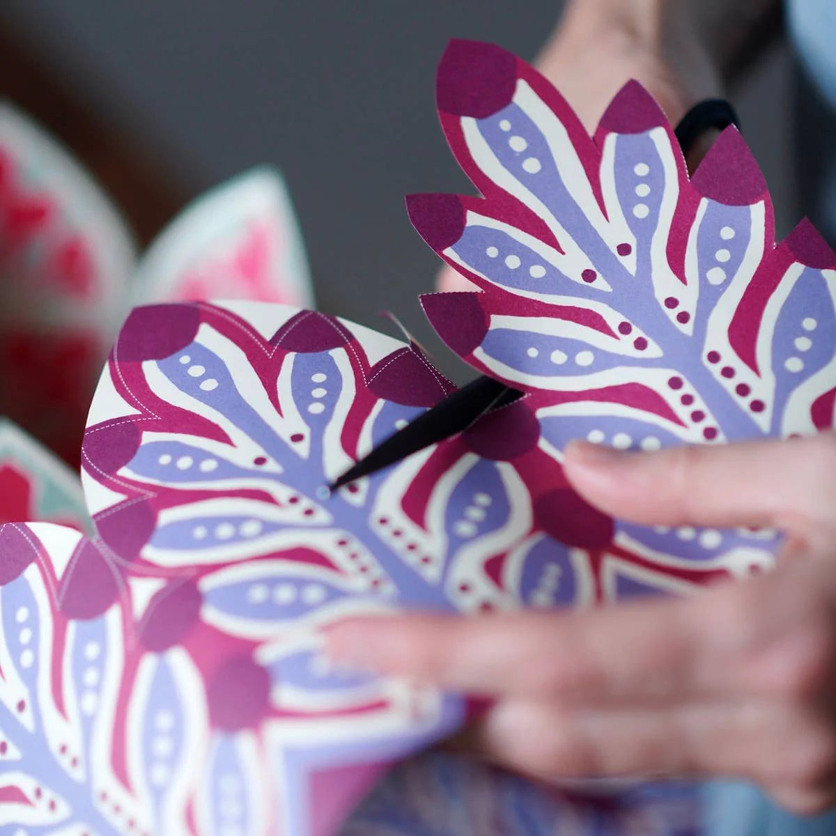 Person holding a pink and purple floral-patterned box with another similar box in the background.