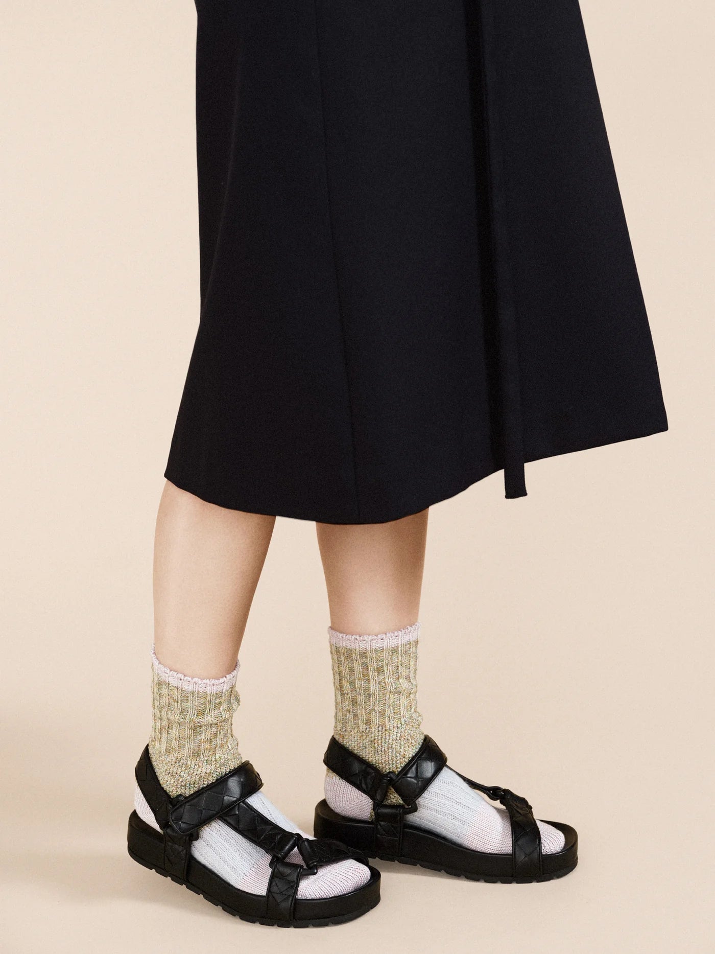 Pixie Dapple Crew socks in Pastel — sage and gold slub cotton crew with white toe and pink rolled cuff, worn with black platform sandals under a black midi skirt on a cream background
