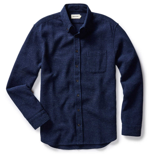 Flat lay of The Jack in Indigo Waffle by Taylor Stitch — a deep indigo organic cotton button-down shirt with waffle texture, button-down collar, chest pocket, and dark buttons, on a white background