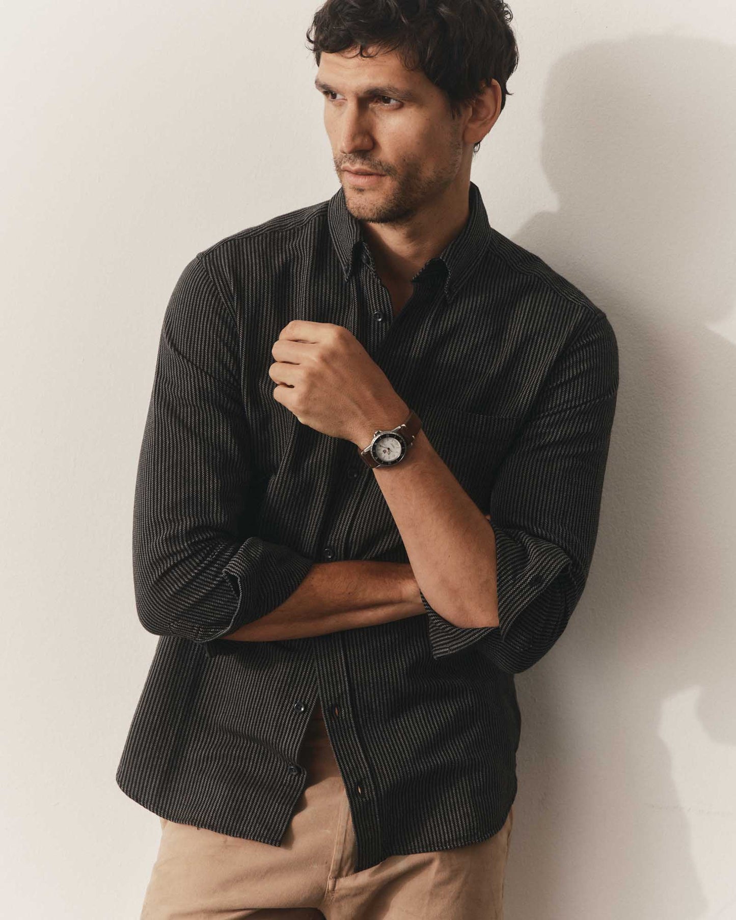 The Jack in Roped Black Indigo by Taylor Stitch, front lifestyle view, model wearing the shirt open at collar with sleeves rolled, paired with khaki trousers