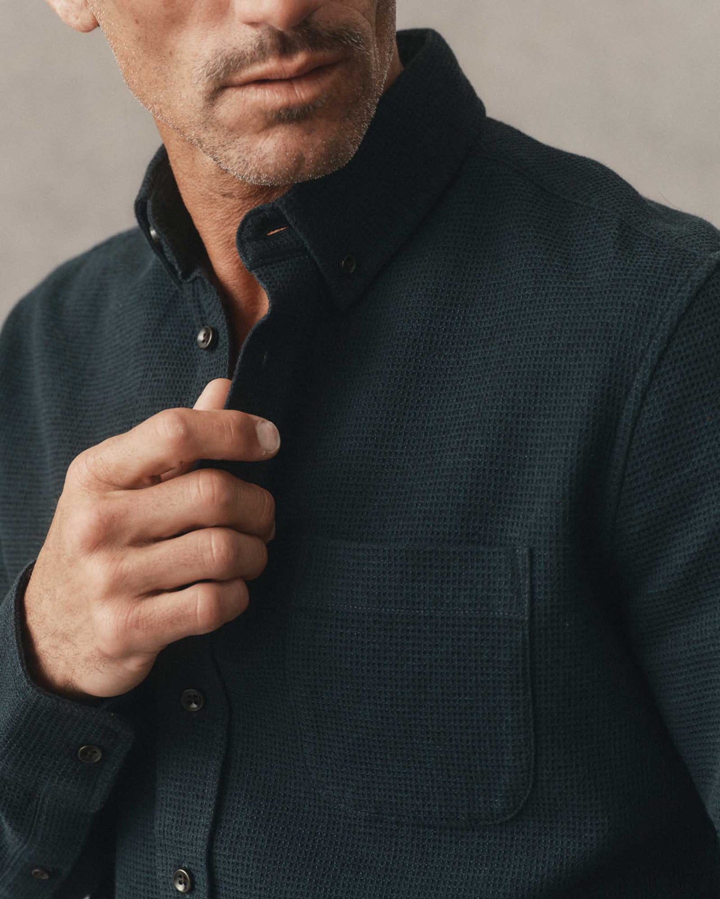 Close-up of male model wearing the Taylor Stitch Jack Shirt in Forest Waffle, showing button-down collar, chest pocket, and organic cotton waffle texture in dark forest green