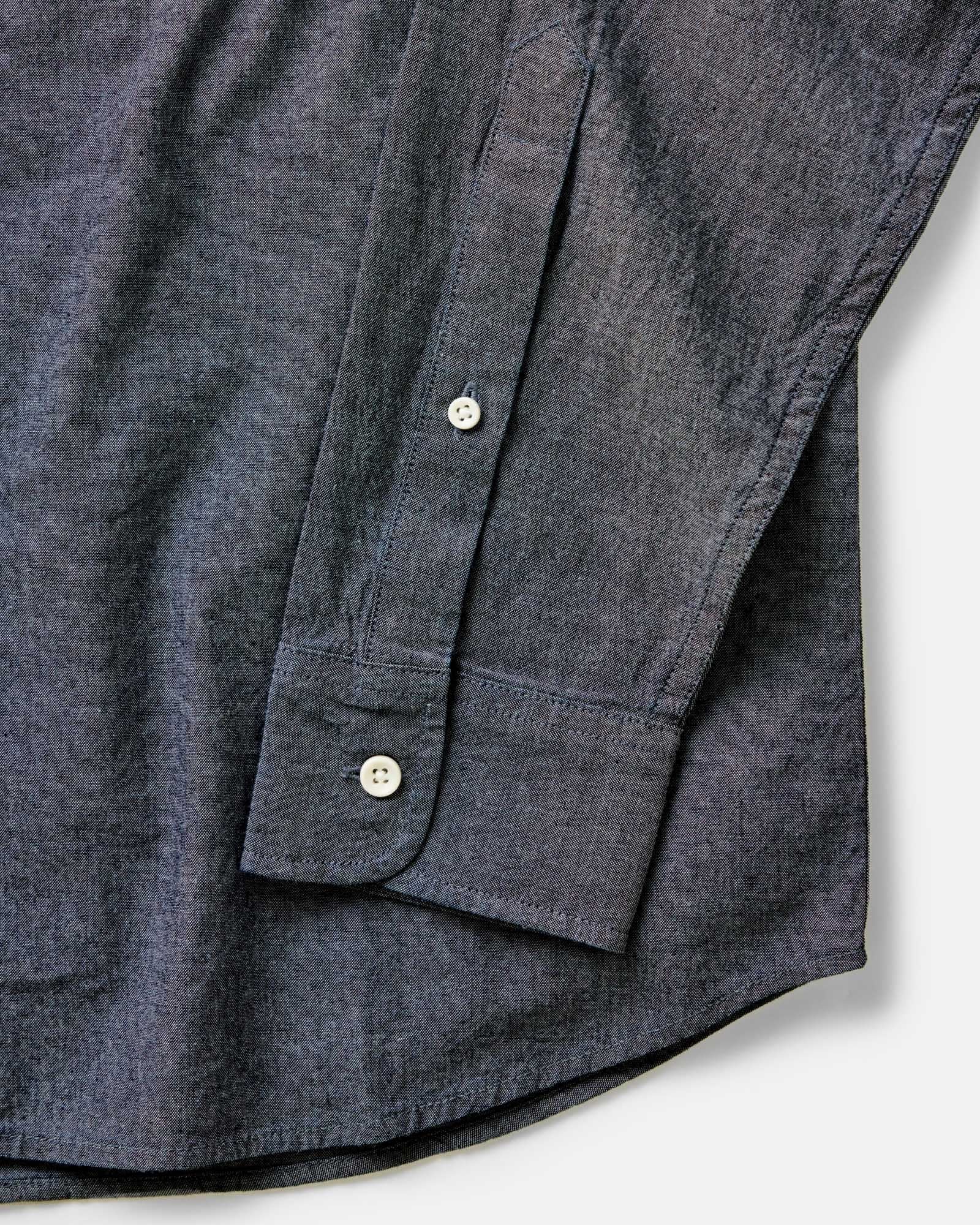 Close-up detail of The Jack in Rinsed Indigo Chambray showing barrel cuff, natural buttons, and double-needle felled construction on a white background