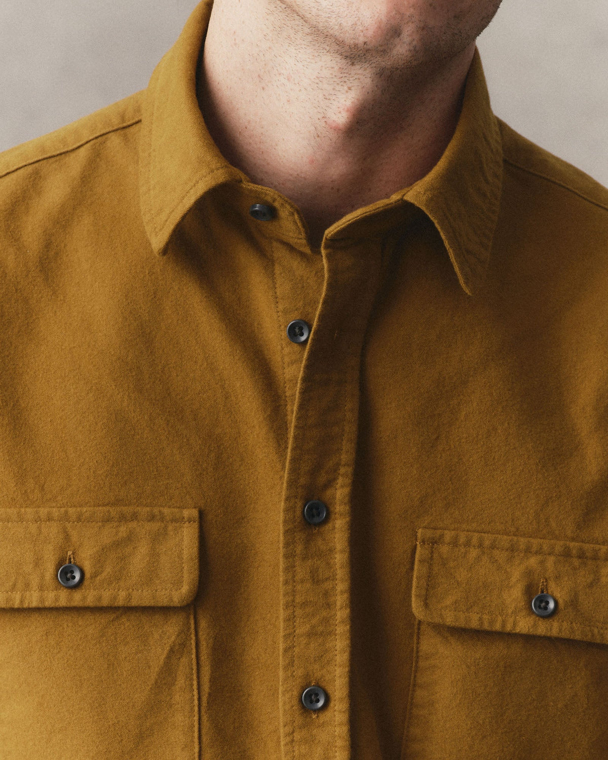 Close-up of the Yosemite Shirt in Saffron on a model, showing the collar, cotton chamois texture, and button-flap chest pockets.
