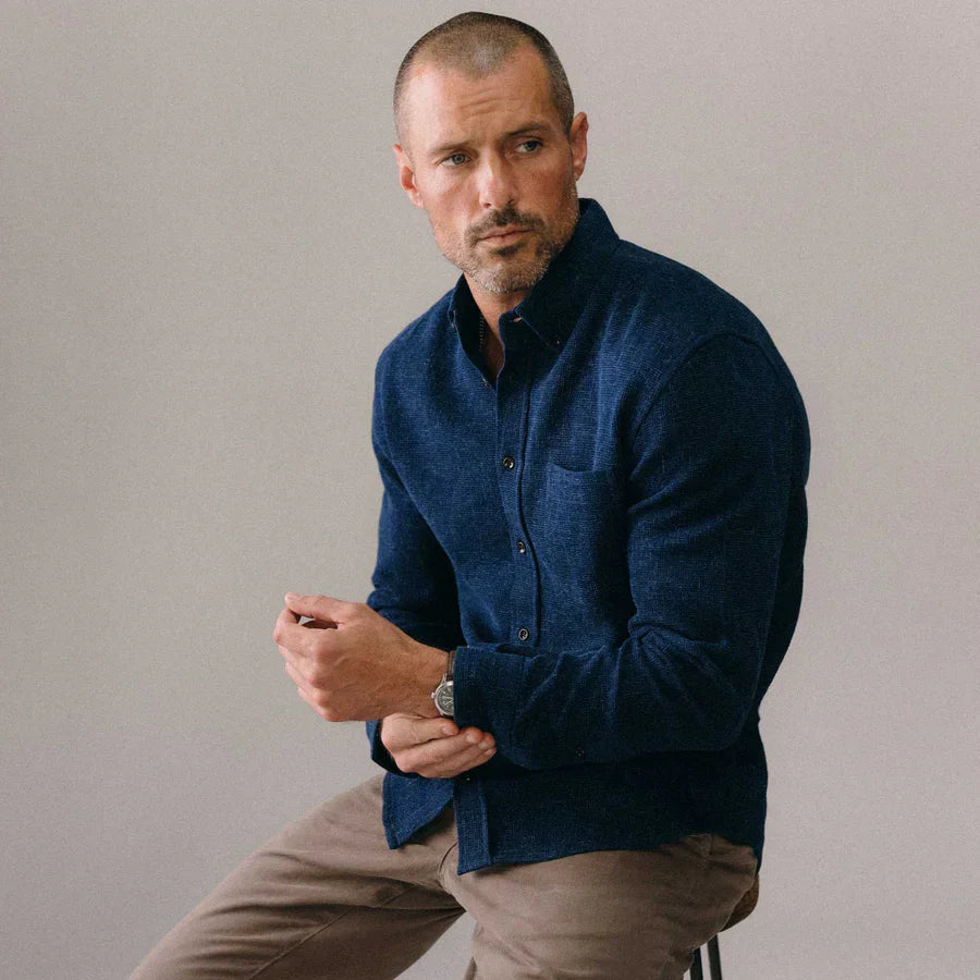 On-model front view of The Jack in Indigo Waffle by Taylor Stitch, worn open over a dark shirt, styled with khaki pants. Model is seated and adjusting the cuff