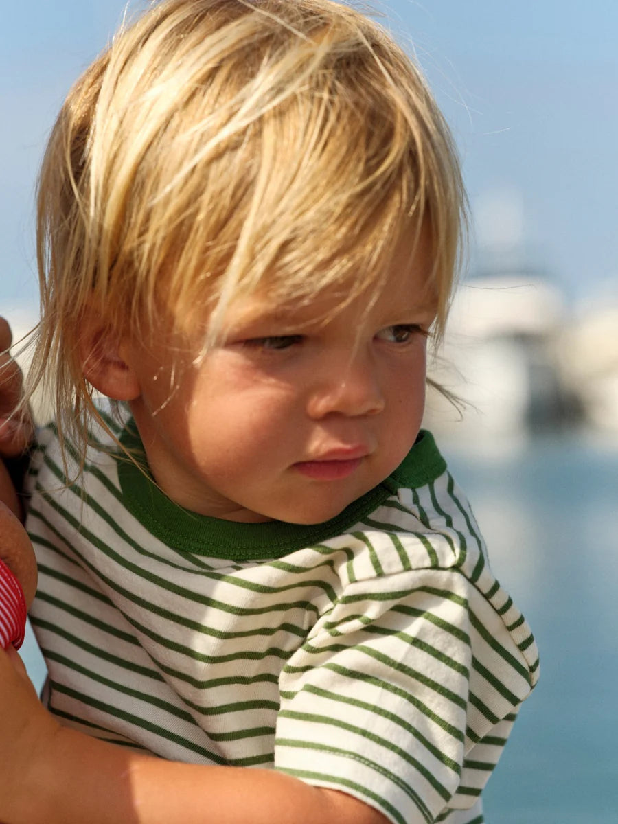 Child wearing a green and white striped shirt with a blurred background