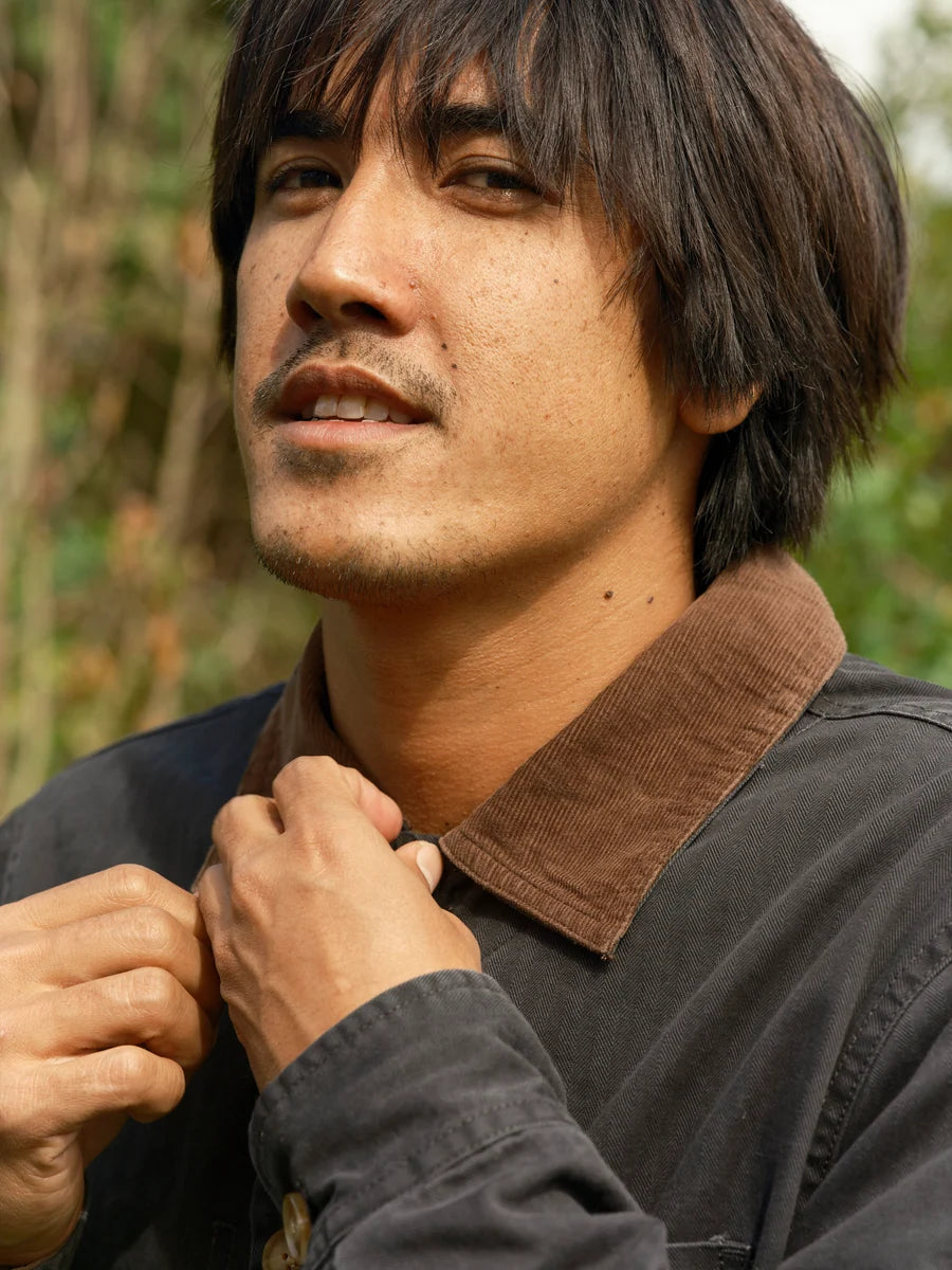 Close-up of the navy Lined Builder Jacket's brown corduroy collar and herringbone twill fabric on a model.
