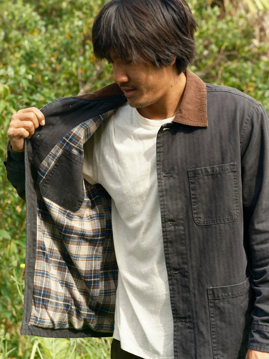Model holding the navy Lined Builder Jacket open to show its plaid flannel lining and interior chest pocket.
