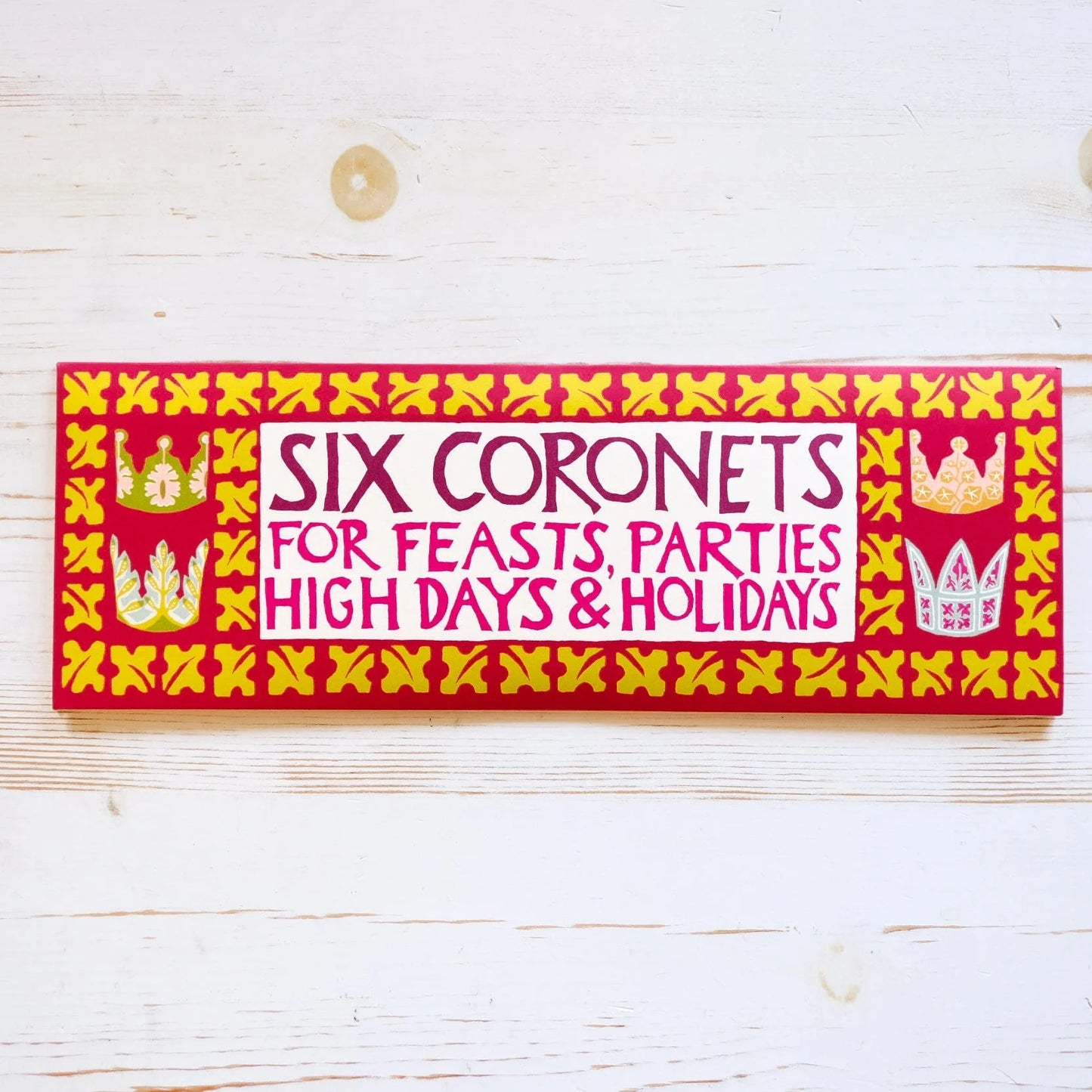 Decorative label with text 'Six Coronets for Feasts, Parties High Days & Holidays' on a wooden surface.