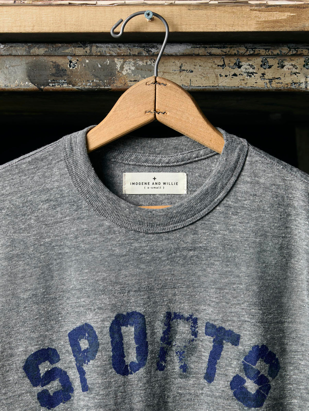 Neckline close-up showing Imogene and Willie label, ribbed crew neck, and top of the 'SPORTS' printed tee