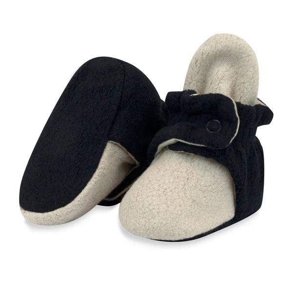 Khaki/Black fleece baby booties, with one upright showing its snap strap and the other tilted to show its plain black sole.
