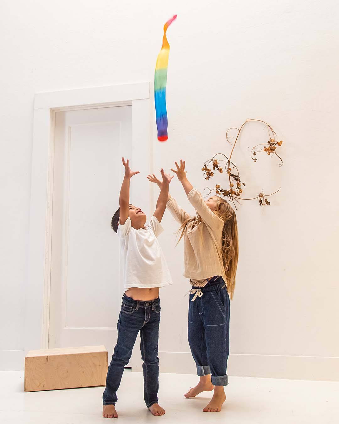 Two children reaching with their hands extended to the sky to catch the skytail.
