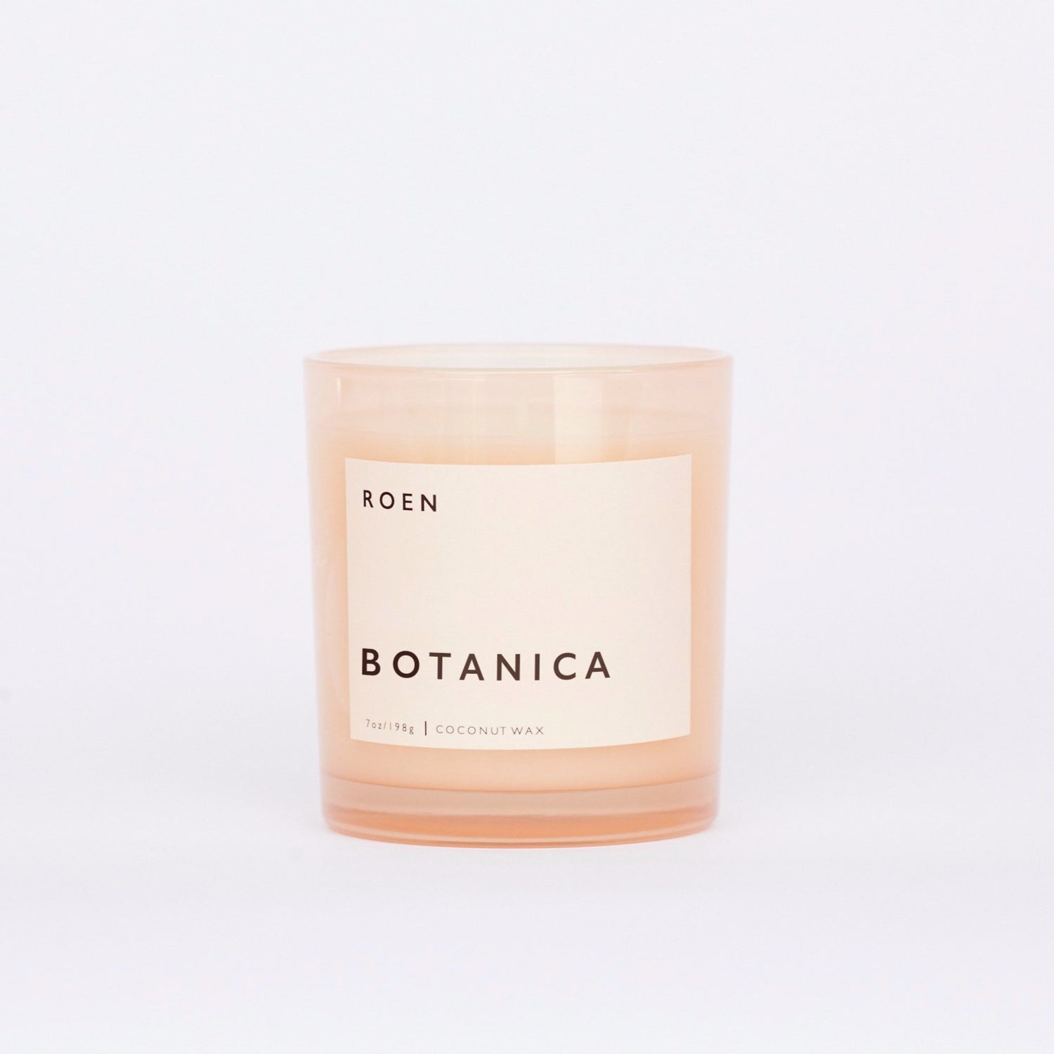 Front facing shot of Roen's Botanica scented candle in a pink glass jar with a light pink label and black font reading "Botanica".