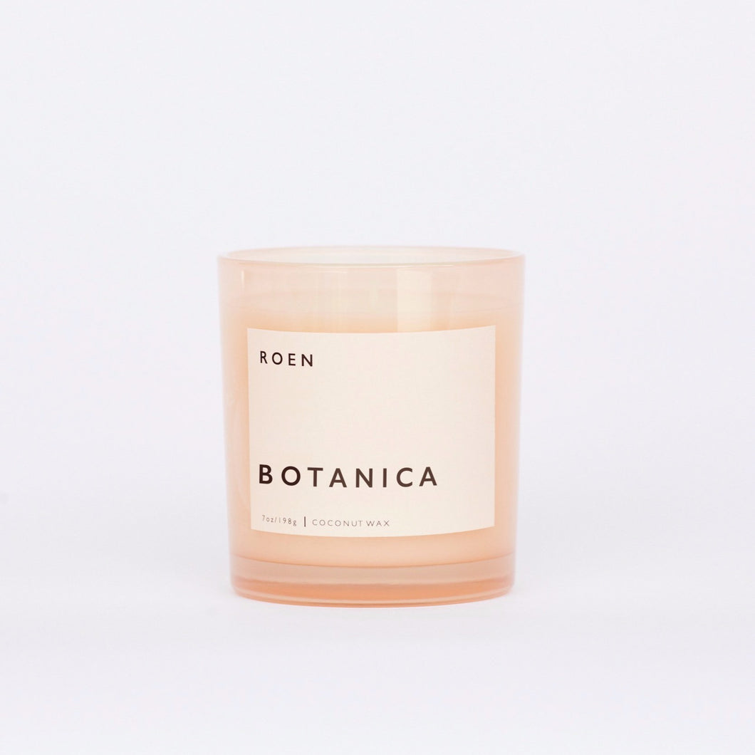 Front facing shot of Roen's Botanica scented candle in a pink glass jar with a light pink label and black font reading 