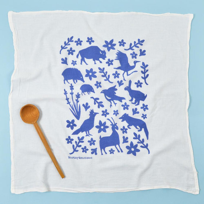 Photograph of a dishtowel with blue animals and flours printed on it.