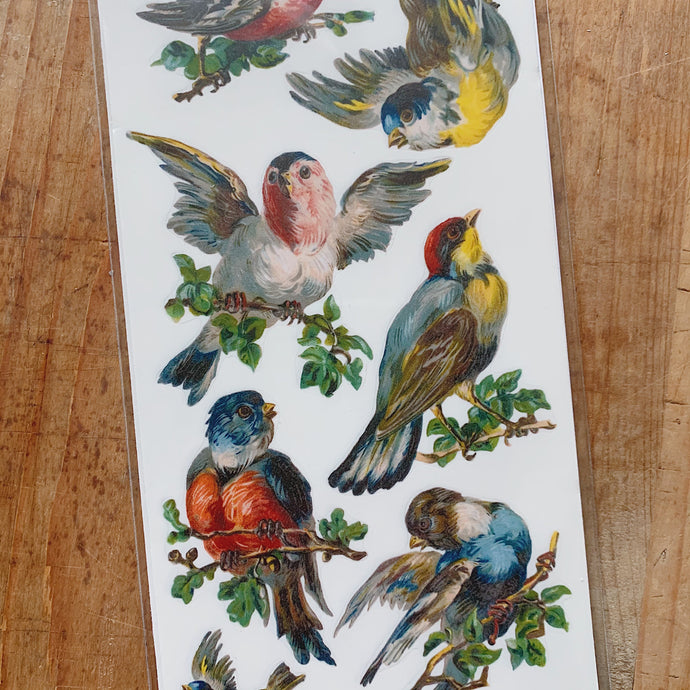 Overhead close up view of stickers of colorful swallowtail birds perched on branches and in flight