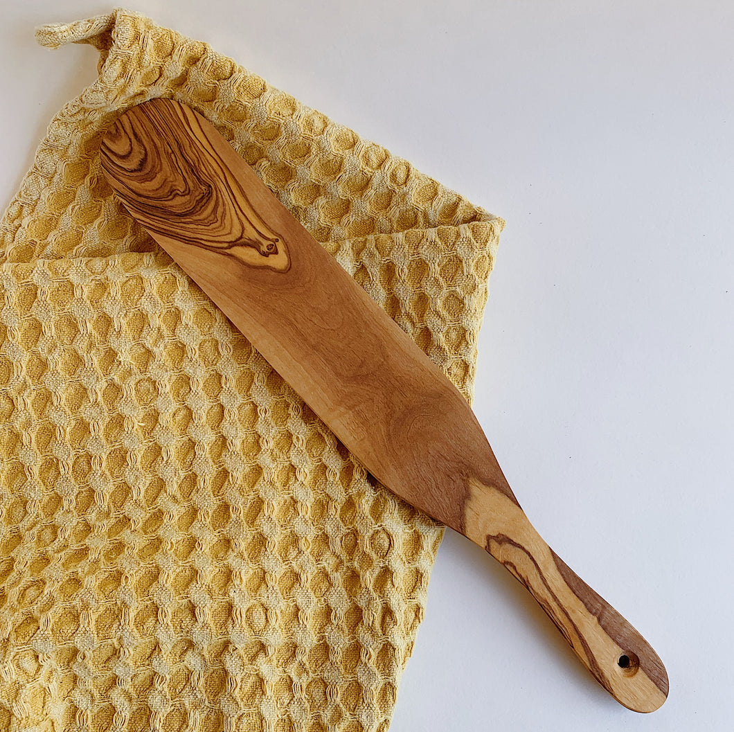wooden spurtle laydown with towel on white background