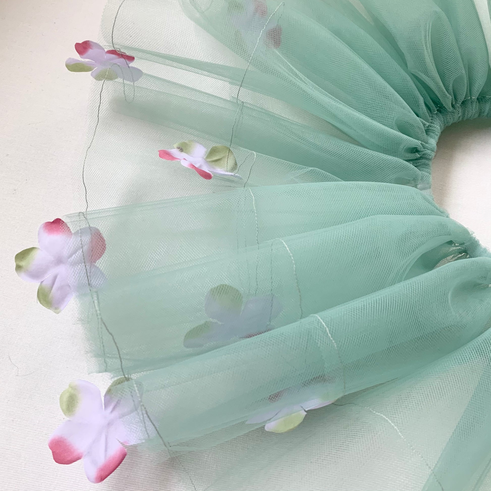 A close-up of the sage green tutu with elastic waistband and lavender petals